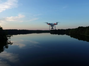 Drohne fliegt bei Abenddämmerung über einen grossen See.